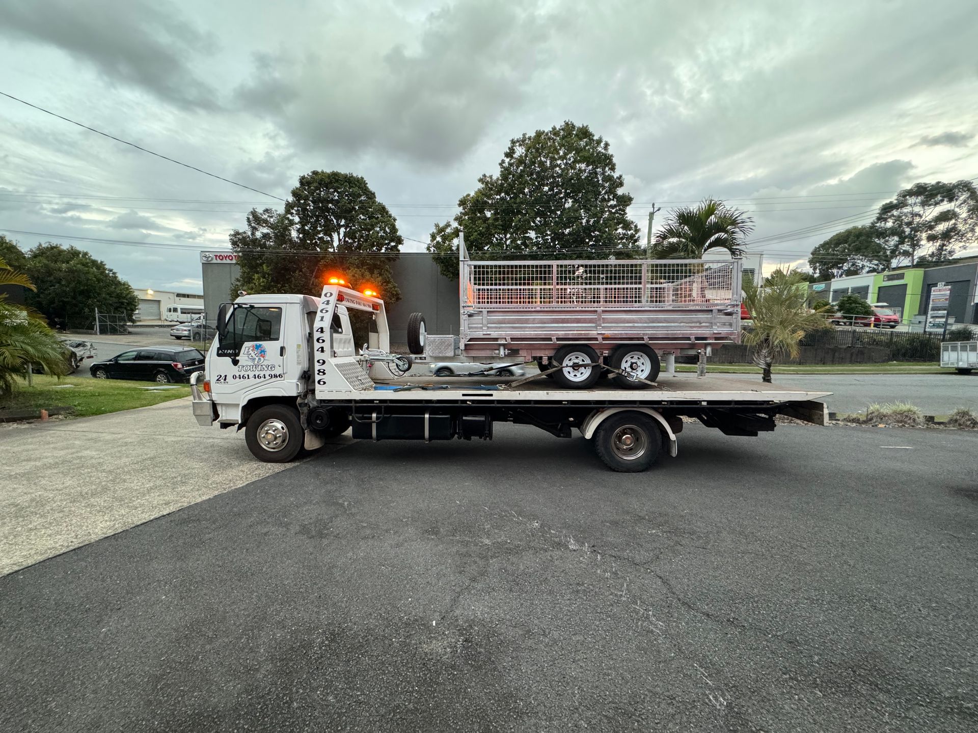 Tow Truck With a Trailer on Its Flatbed, Parked Outside. Overcast Sky — B&D Auto Group & Towing in Collinsville, QLD