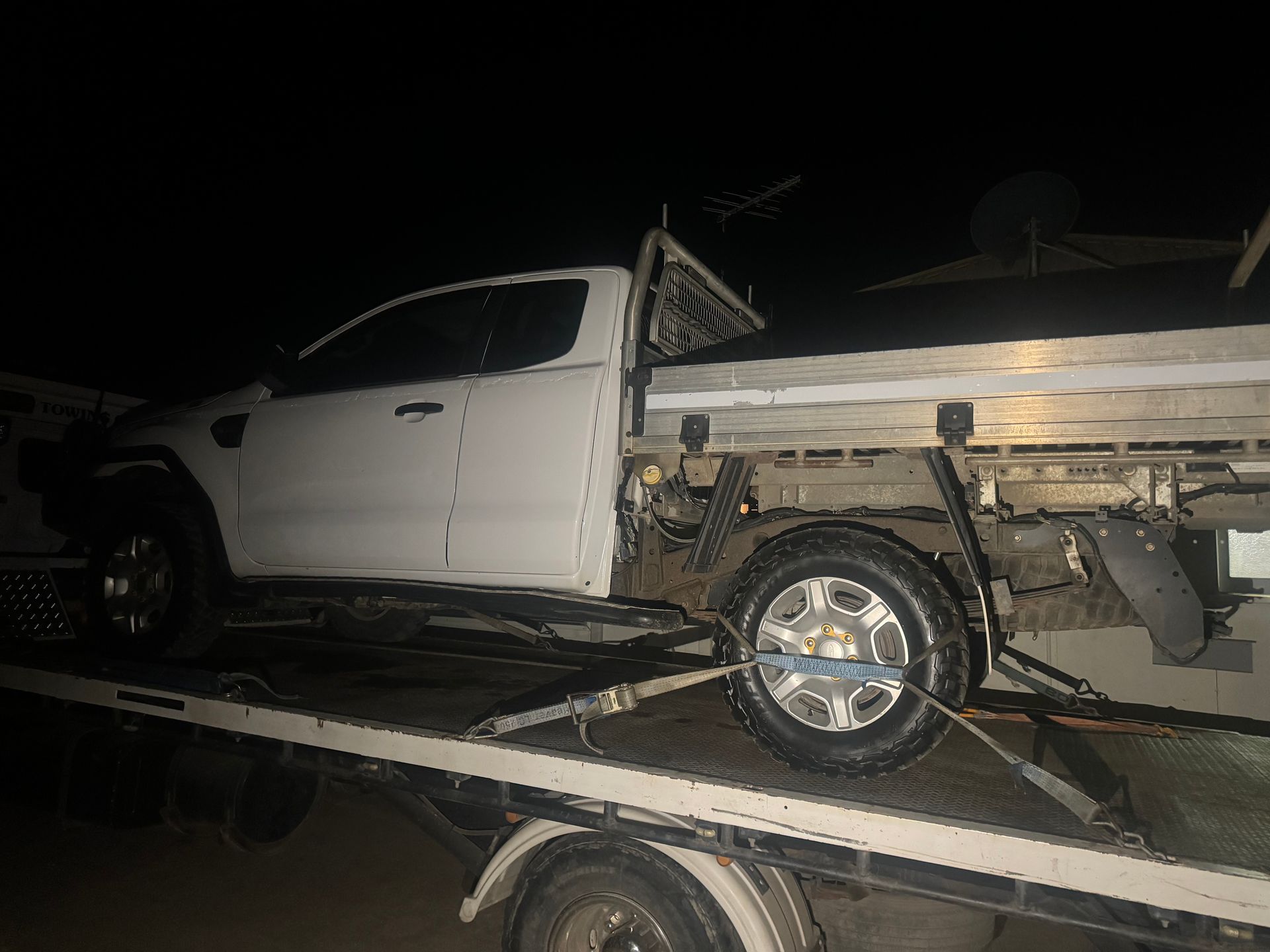 White Pickup Truck on a Tow Truck at Night, Secured With Straps — B&D Auto Group & Towing in Airlie Beach, QLD