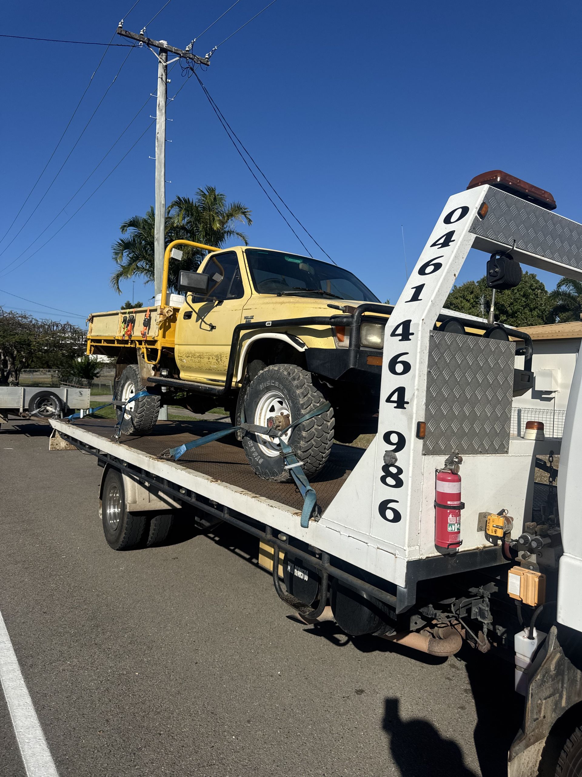 Yellow Truck on a Tow Truck, Parked on Pavement With a Phone Number Displayed — B&D Auto Group & Towing in Bowen, QLD