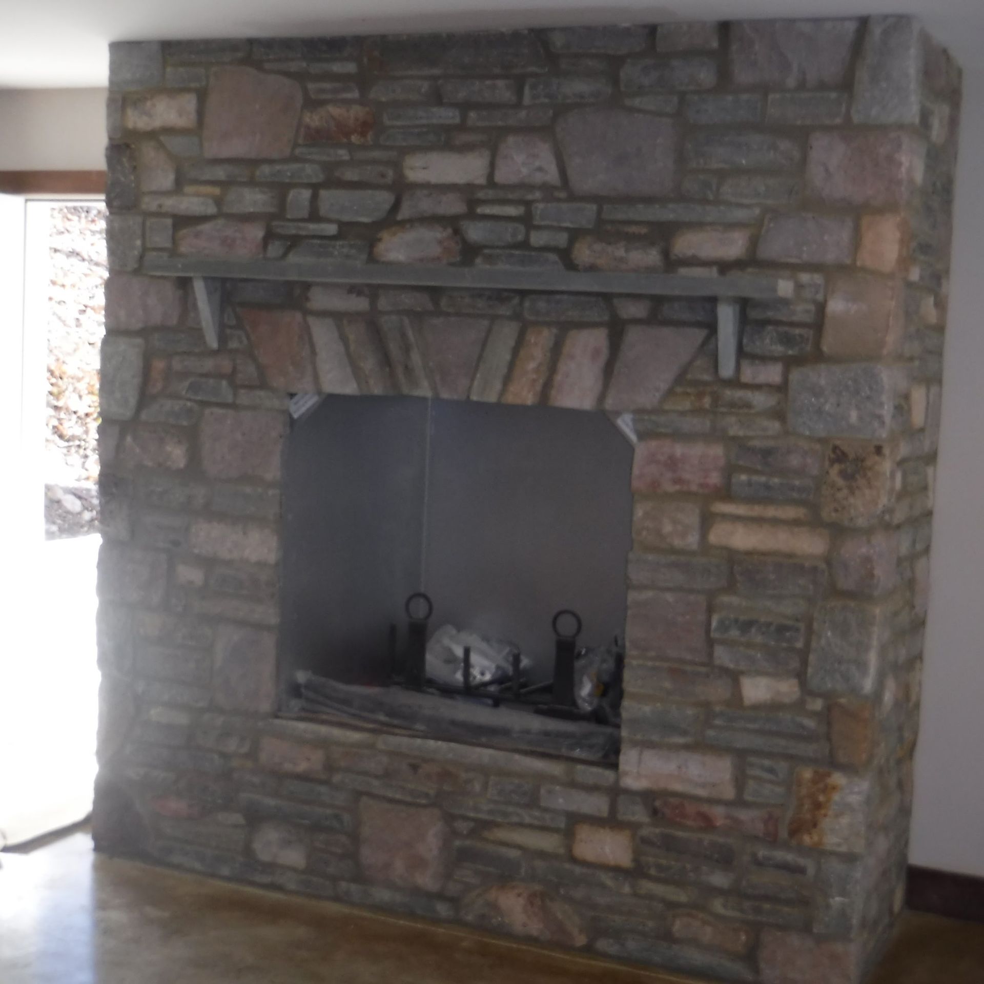 Stone fireplace with a dark metal firebox and arched stonework in a room