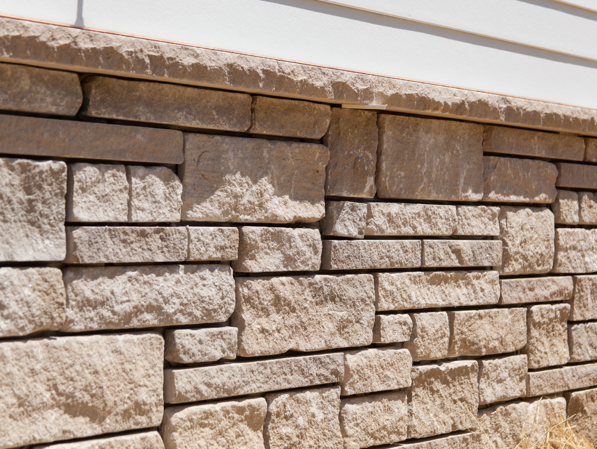 Snow-dusted stacked stone wall with a tan and brown ledge