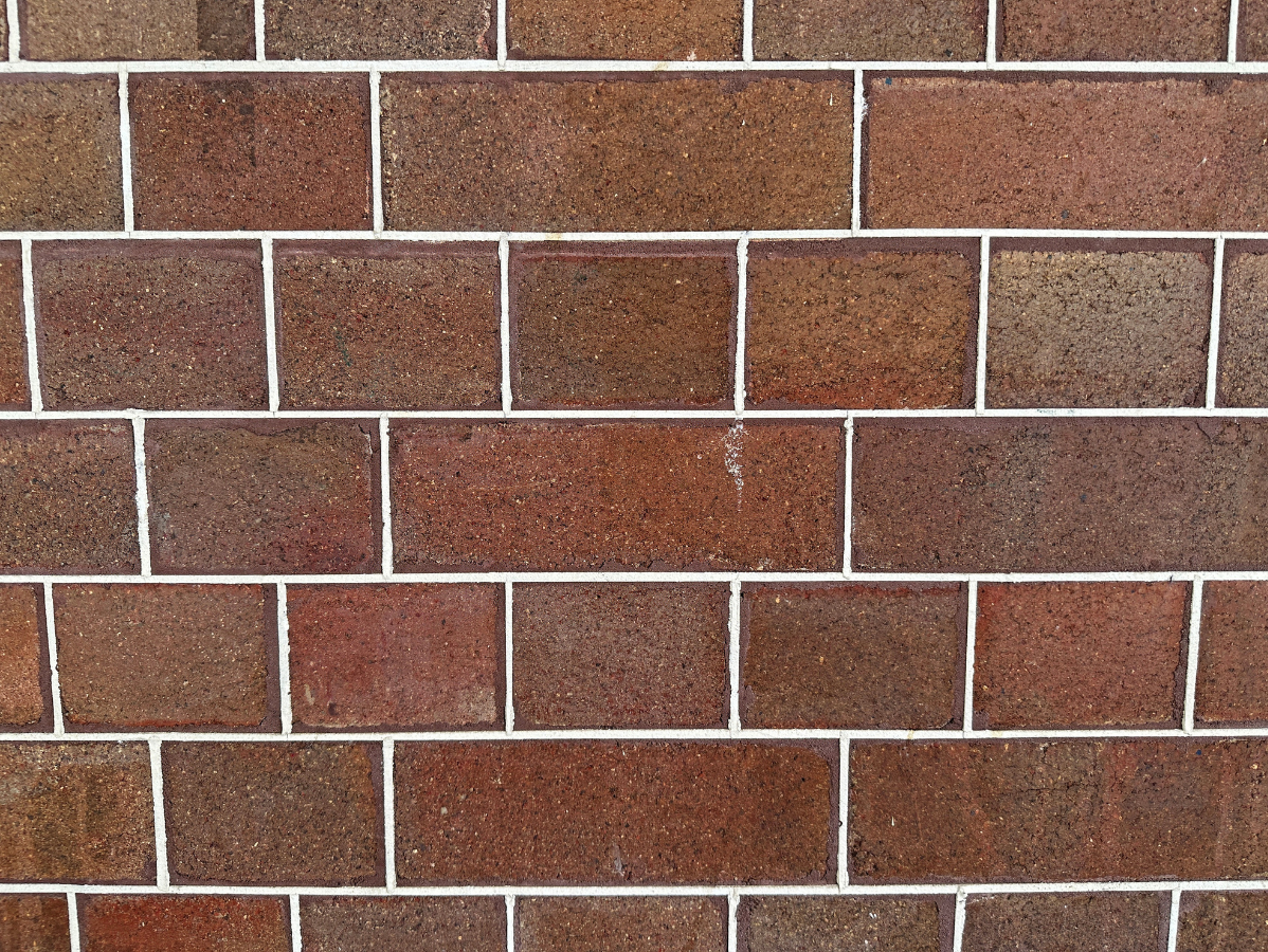 Brown brick wall with light gray mortar lines in a staggered pattern