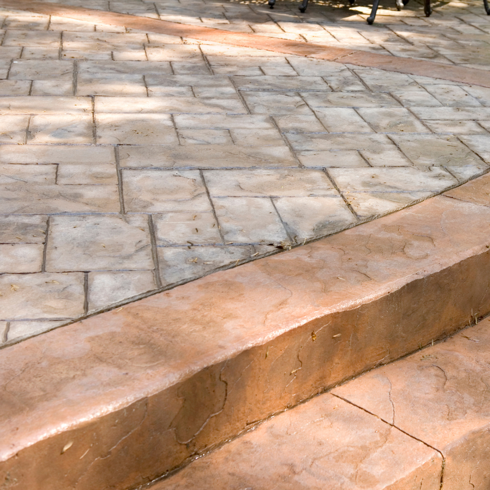 Stone-paved walkway with a low curved curb and visible cracks in the foreground
