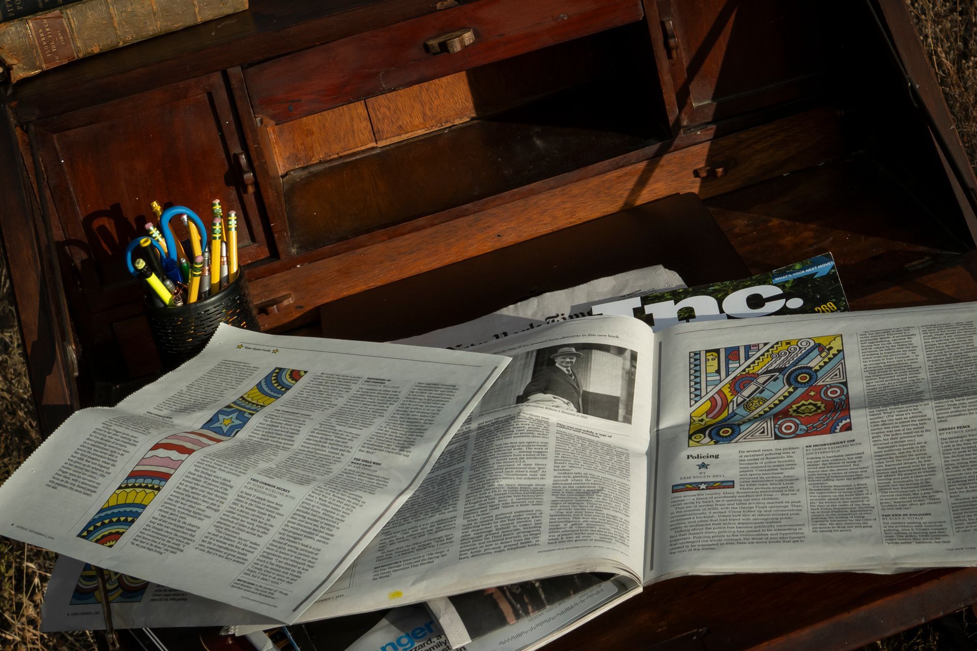 A stack of newspapers sits on top of a wooden desk