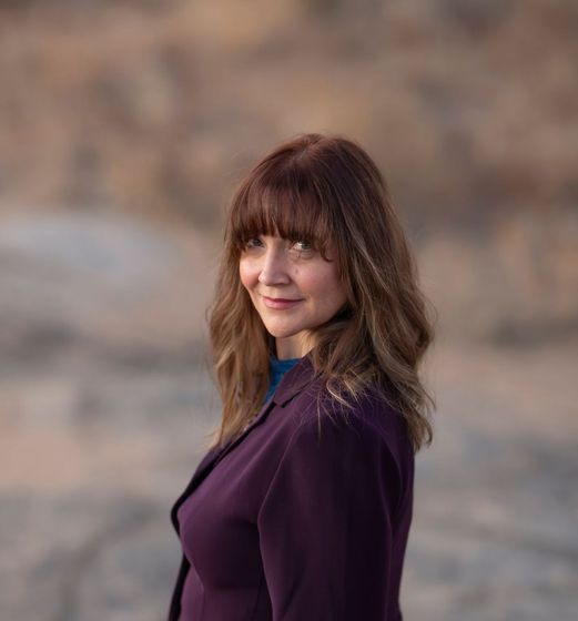 Jessica Michael in a purple jacket smiling.