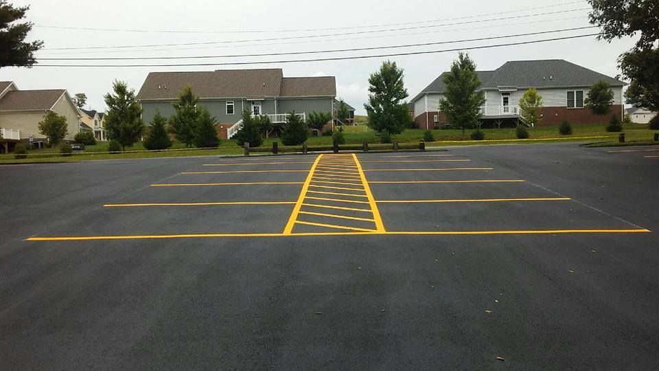 A parking lot with yellow lines on it and houses in the background