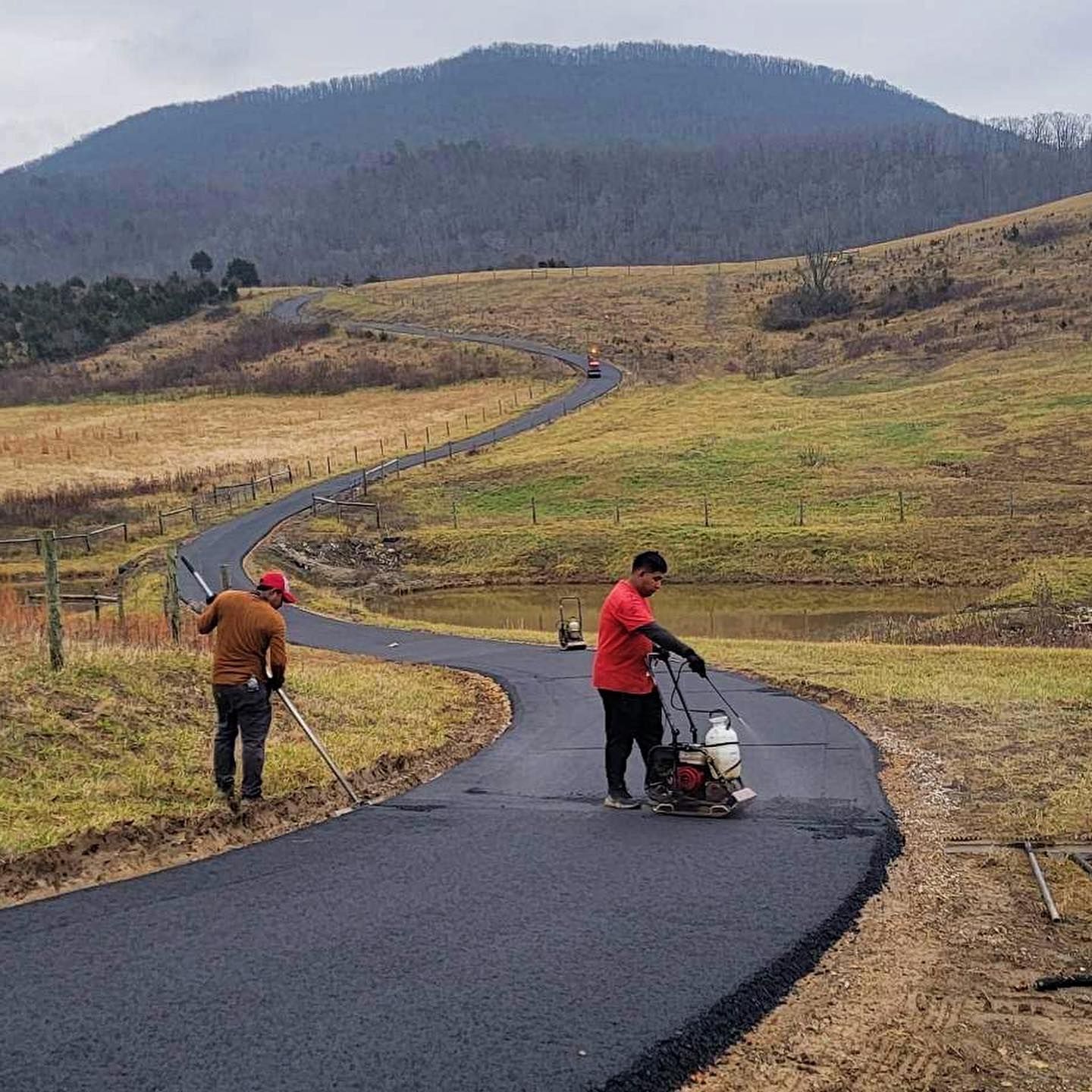 Two men are working on a road in the countryside.