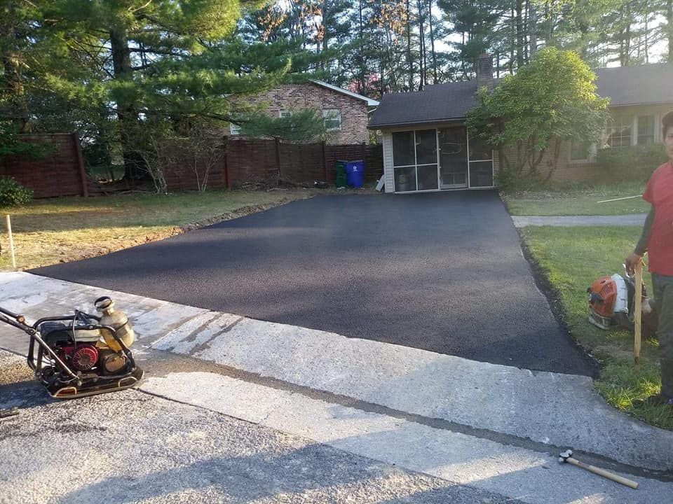 A man is working on a driveway in front of a house.
