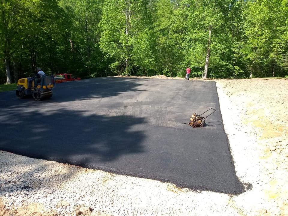 A large piece of asphalt is being rolled out in a driveway.