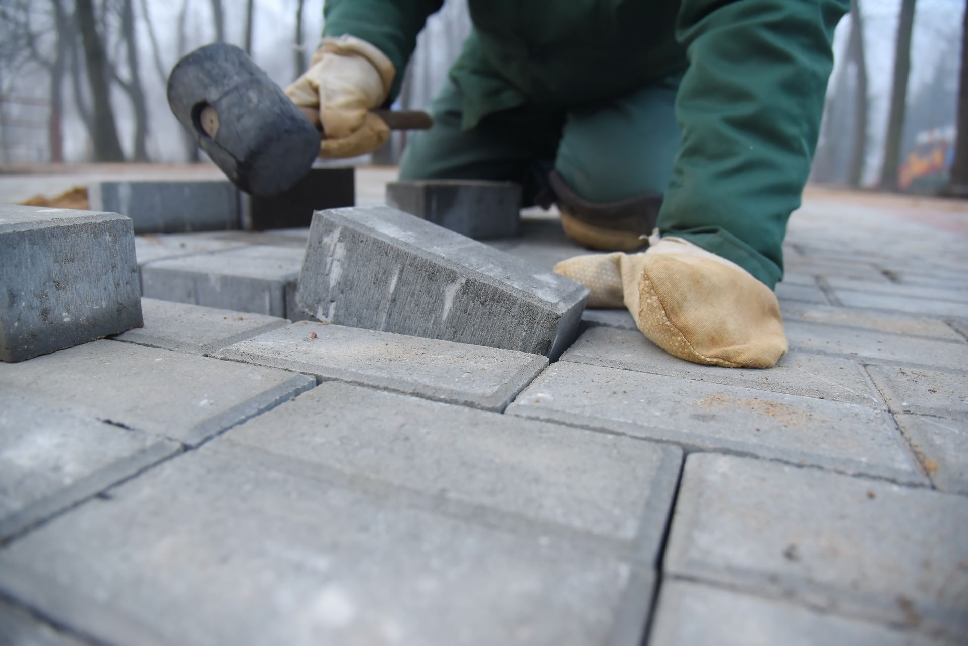 A man lays paving slabs and repairs a road.
