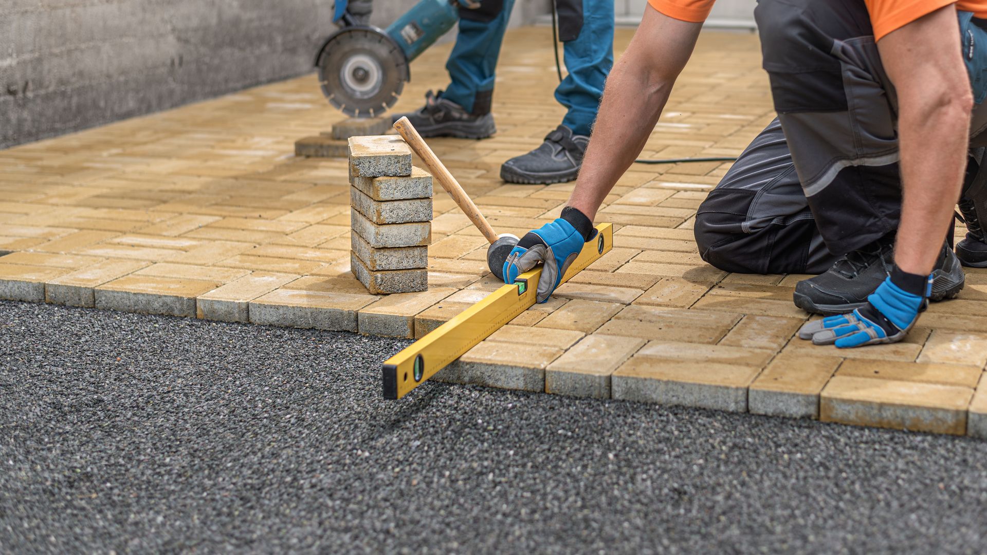 Contractor laying interlocking paving. Leveling the block using a spirit level.