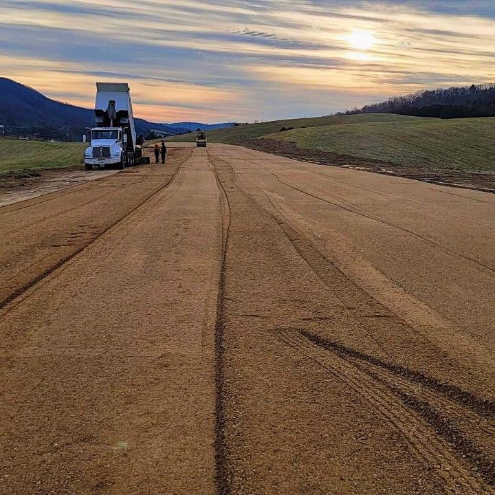 A dump truck is parked on the side of a dirt road.