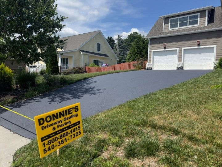 A sign for donnie 's driveway sealing and paving is in front of a house.