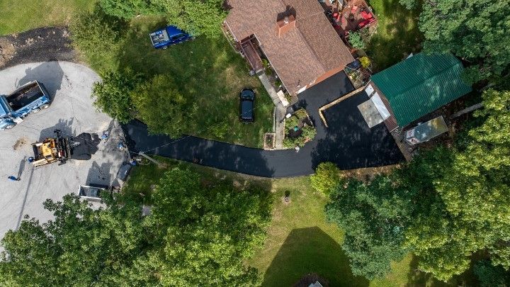An aerial view of a house and driveway being paved.