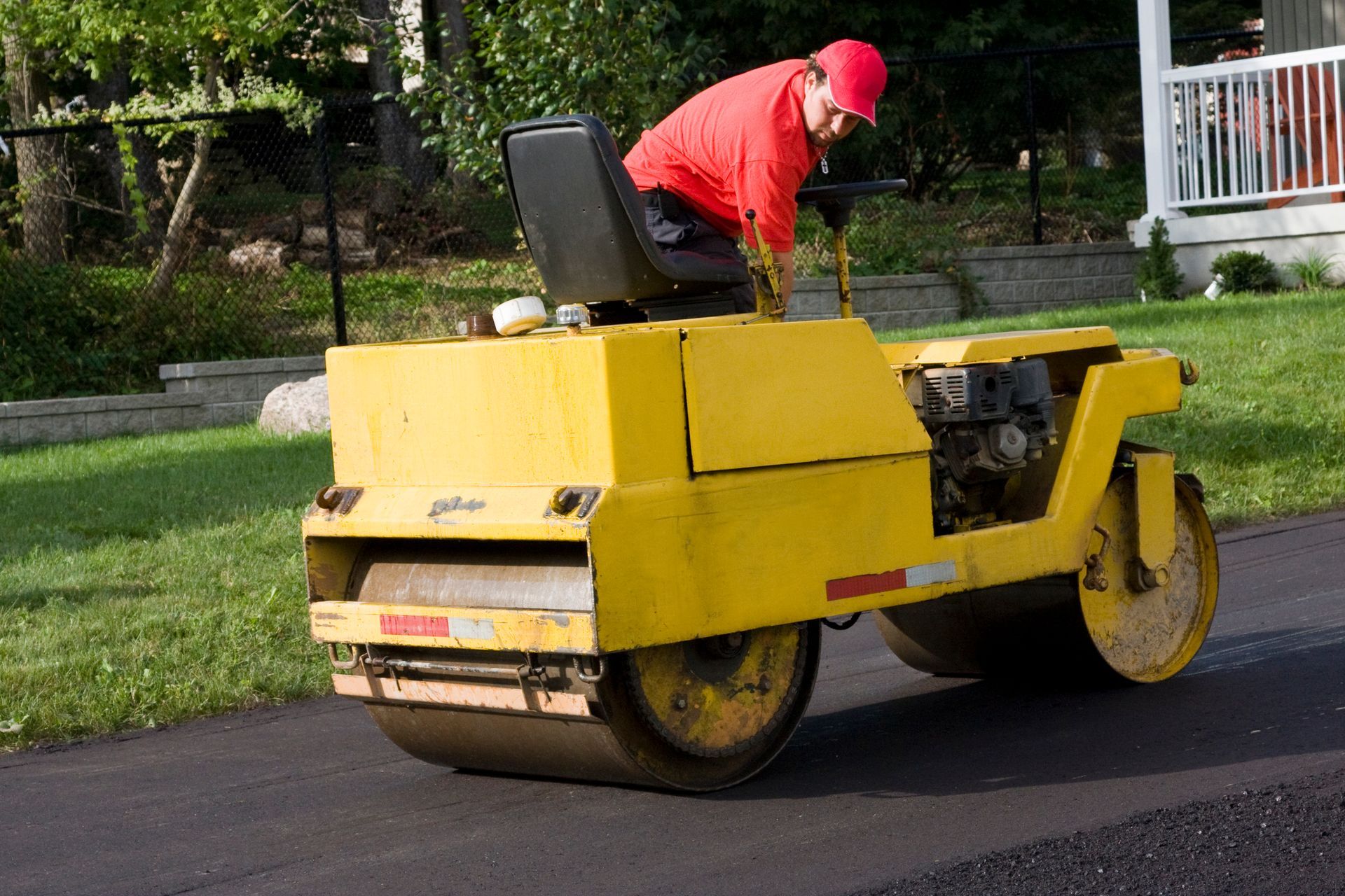 A man is using a roller to finish paving a driveway. A man is using a roller to finish paving a driveway.