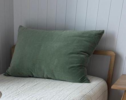 Una almohada verde está encima de una cama.