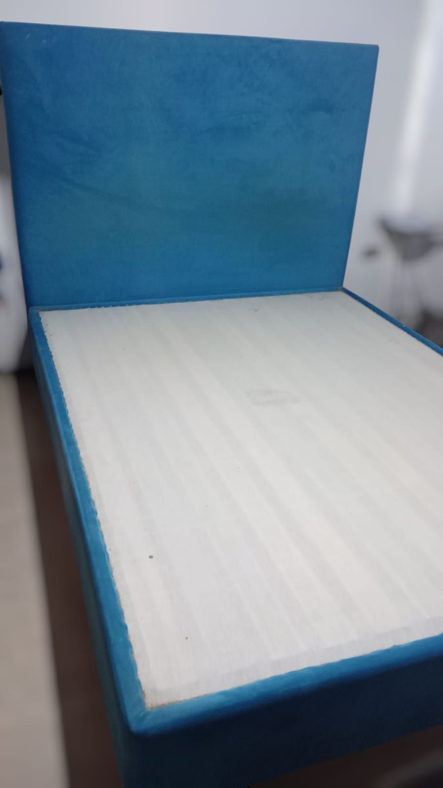 Una cama con cabecera azul y colchón blanco.