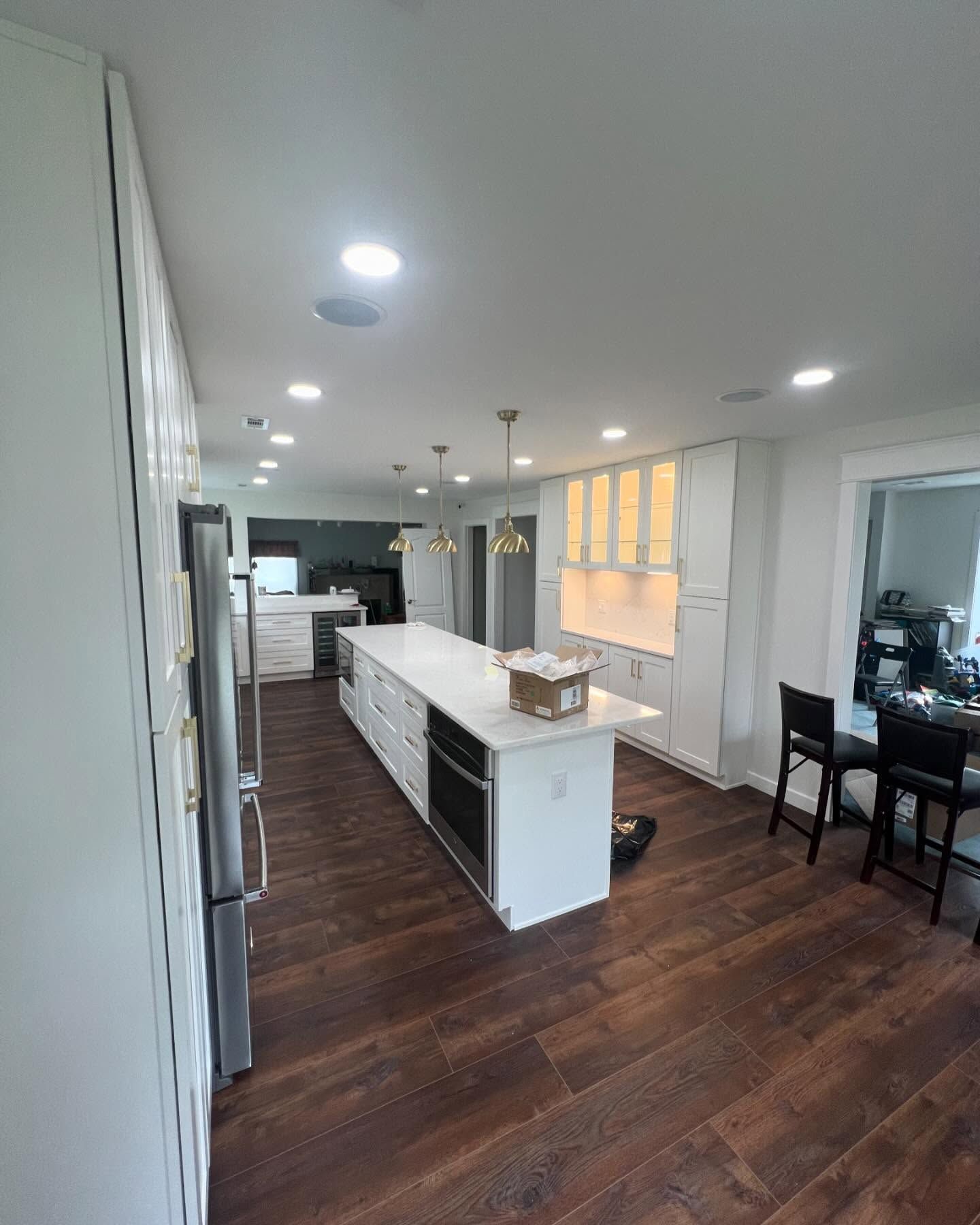 Modern kitchen with white cabinets, island, stainless steel appliances, and wood flooring.