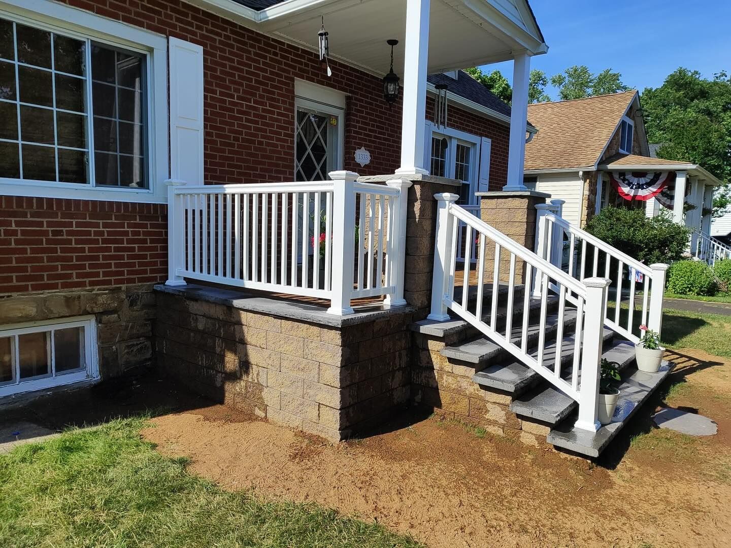 Brick home with white porch railing, steps, and columns.