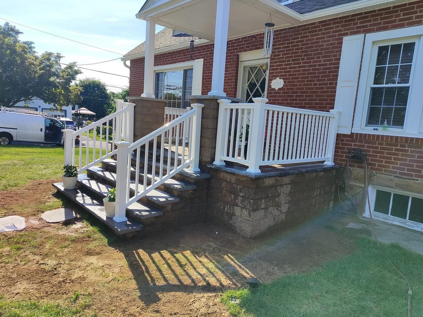 Brick house with white porch, stairs, and railing.