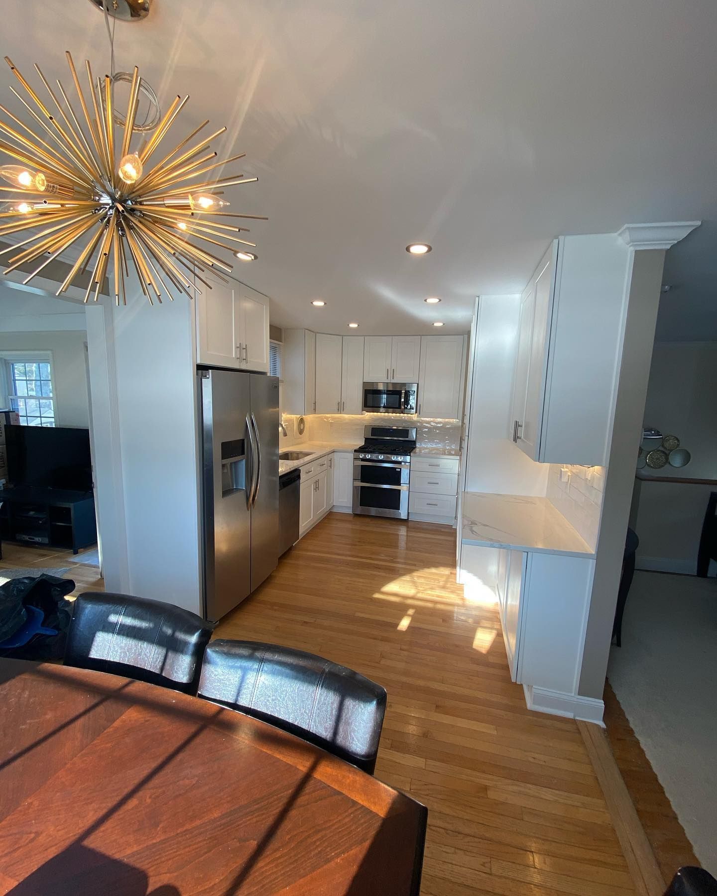 Kitchen with white cabinets, stainless steel appliances, and wooden floors.