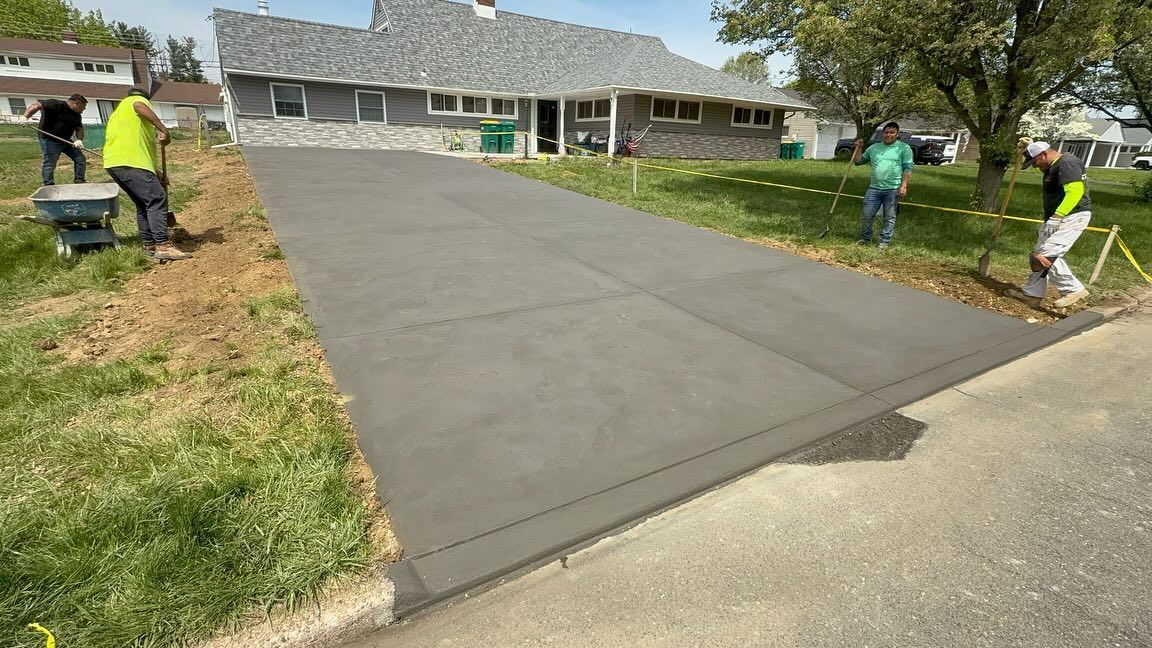 Construction workers pouring concrete for a driveway in front of a house.