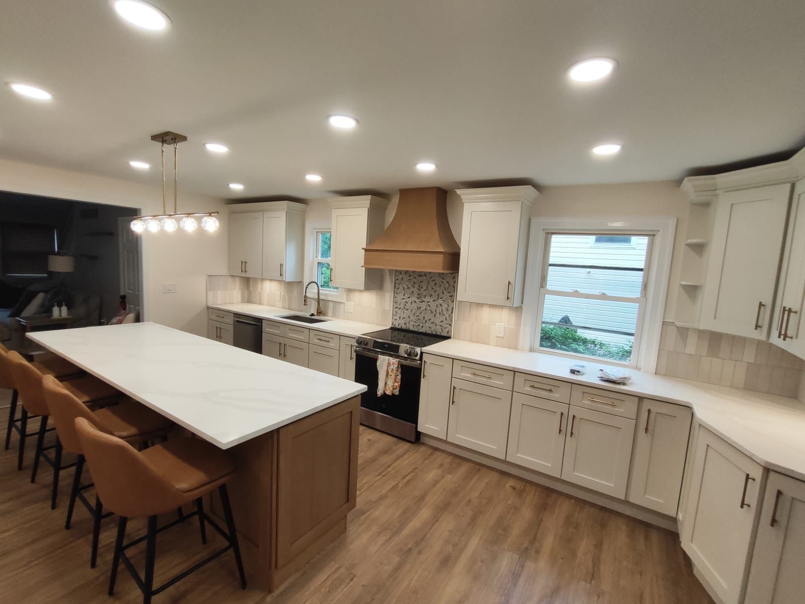 Modern kitchen with white cabinets, wood accents, and a large island with seating.