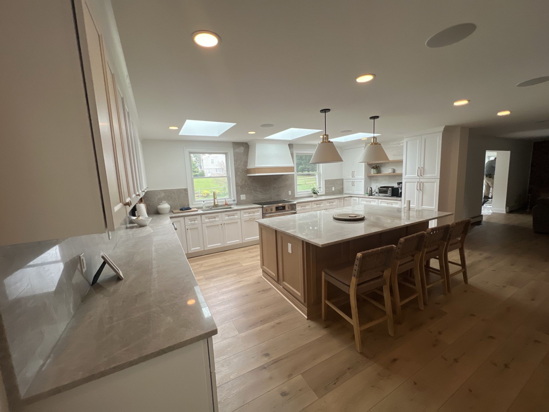 Spacious kitchen with island, wooden floors, white cabinets, and skylights.
