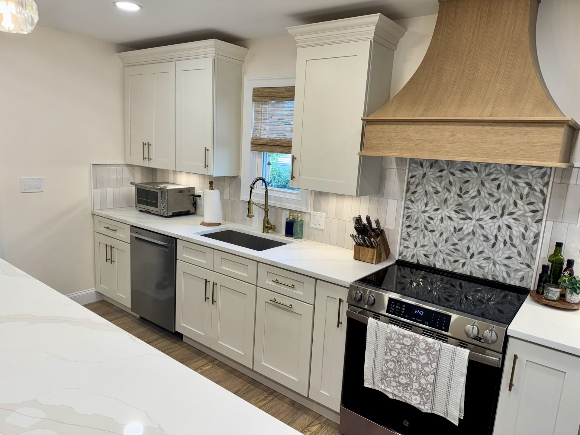 Modern kitchen with white cabinets, stainless steel appliances, and a wooden range hood.