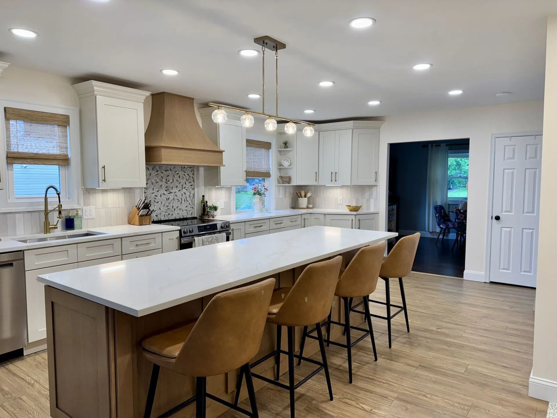 Modern kitchen with large island, light cabinets, wood accents, and bar stools.