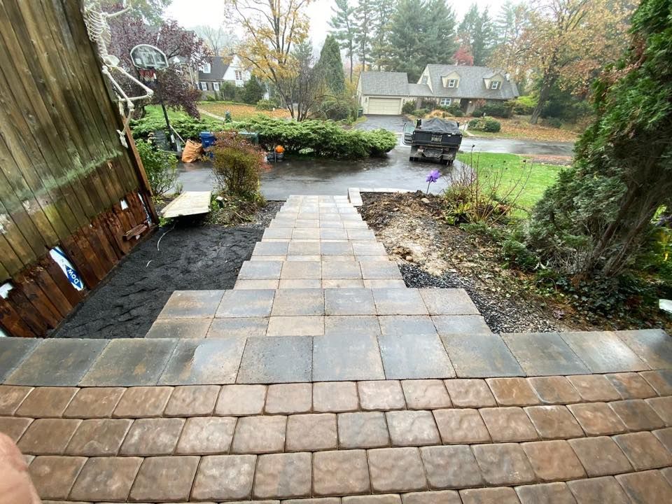 Brick steps leading down to a residential yard with a driveway and surrounding greenery.