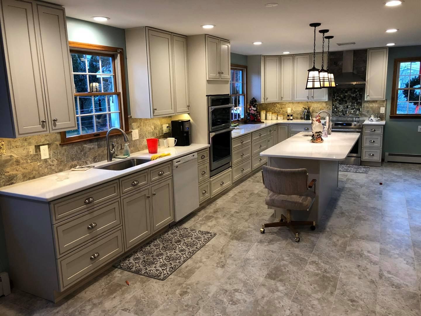 Newly renovated kitchen with gray cabinets, marble countertops, and a central island.