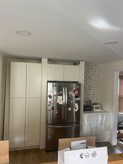 Kitchen with stainless steel refrigerator and white cabinets. A box sits in front.