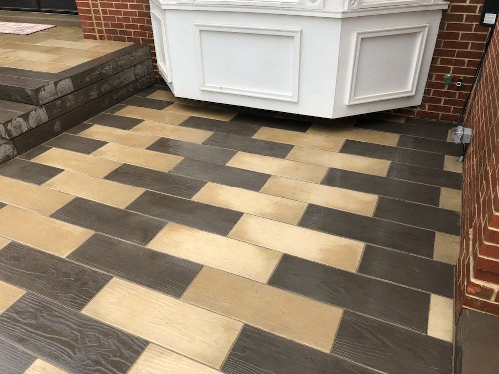 Brown and tan rectangular tile flooring with a white bay window and brick wall.