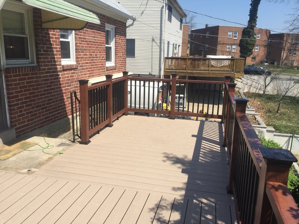 Composite deck with brown railing, attached to a brick building.