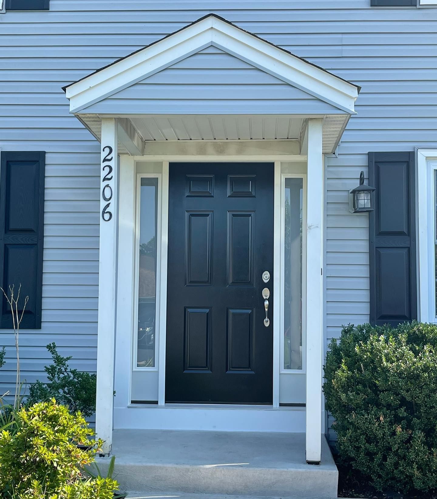 Blue house front door with white trim, black door, and address 2206.