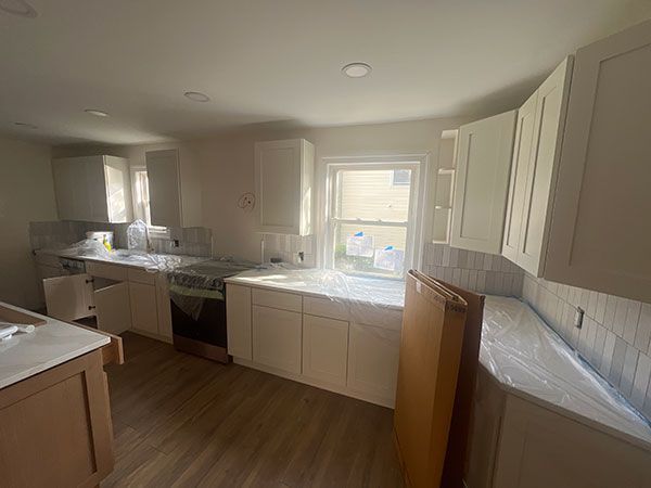 Newly renovated kitchen with white cabinets, light countertops, and wood flooring.