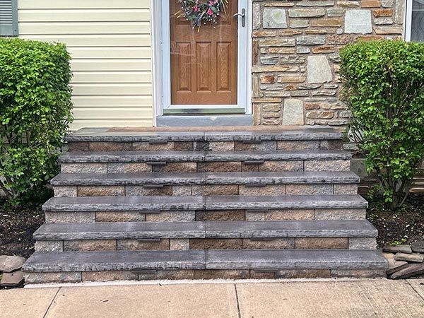 Brick steps leading to a wooden door with a wreath; bushes on either side.