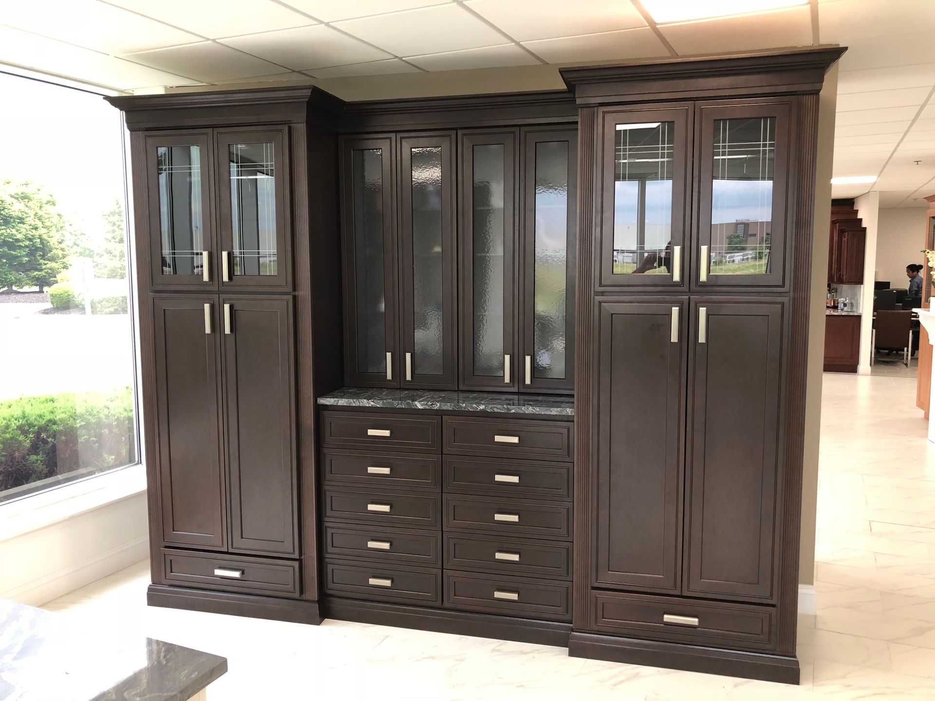 Dark brown cabinetry with glass-fronted upper cabinets, drawers, and a granite countertop.