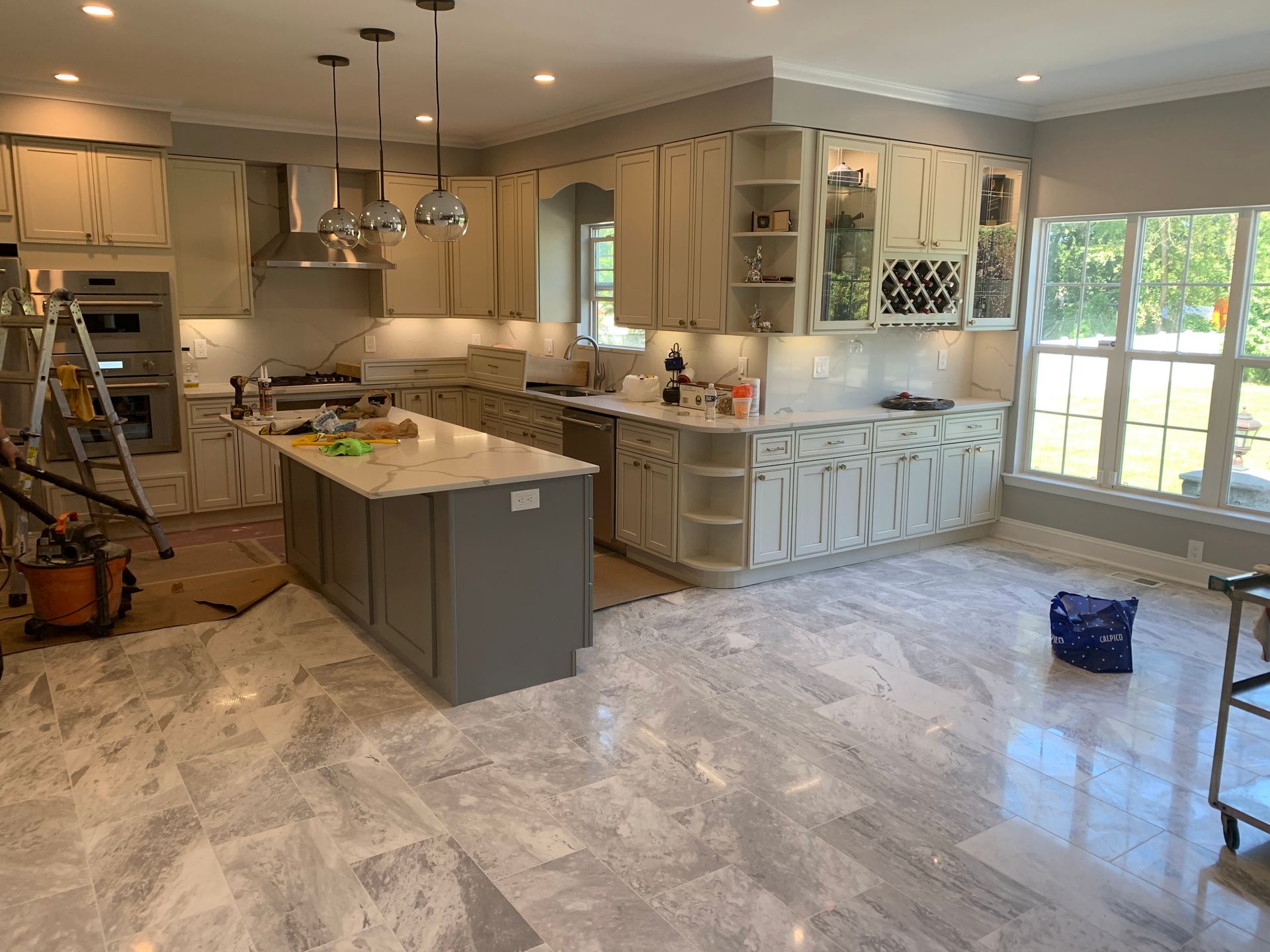 Modern kitchen with white cabinets, wood accents, large island with seating, and stainless steel appliances.