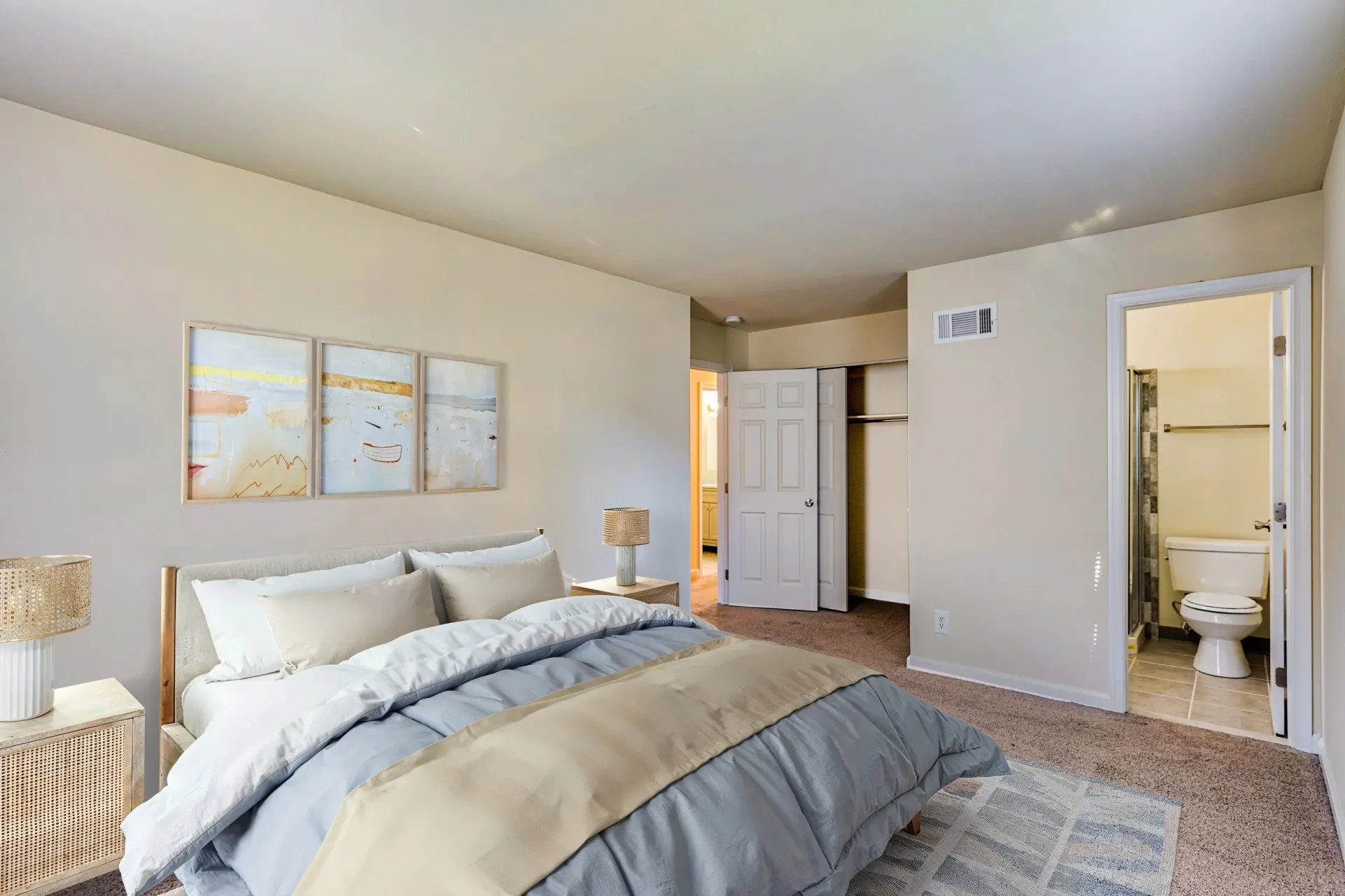 Brookbend Apartments Bedroom with a queen bed, two nightstands, neutral tones, and a doorway to the bathroom.