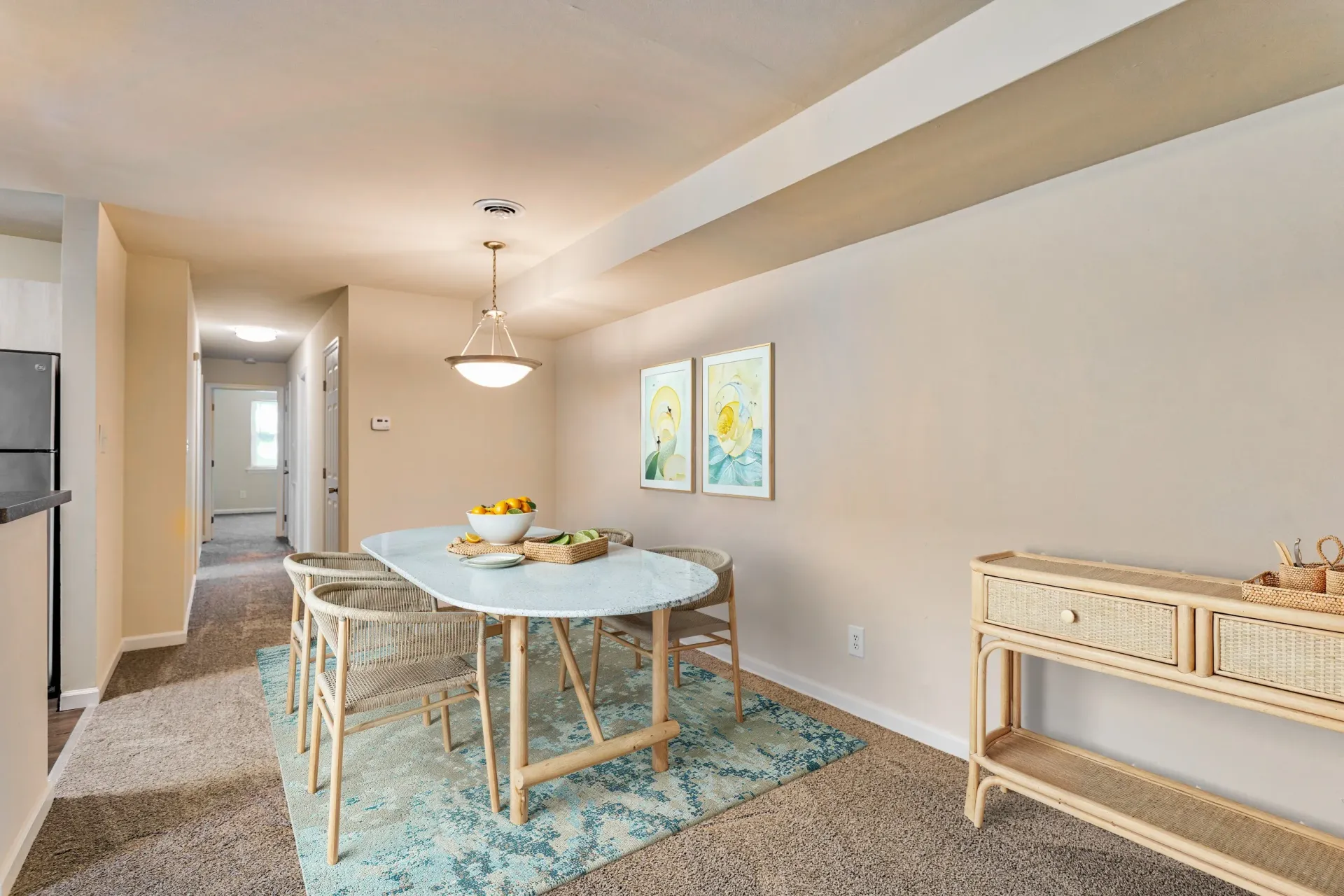 Brookbend Apartments Dining area in an apartment with a table, wicker chairs, and a hallway to the kitchen.