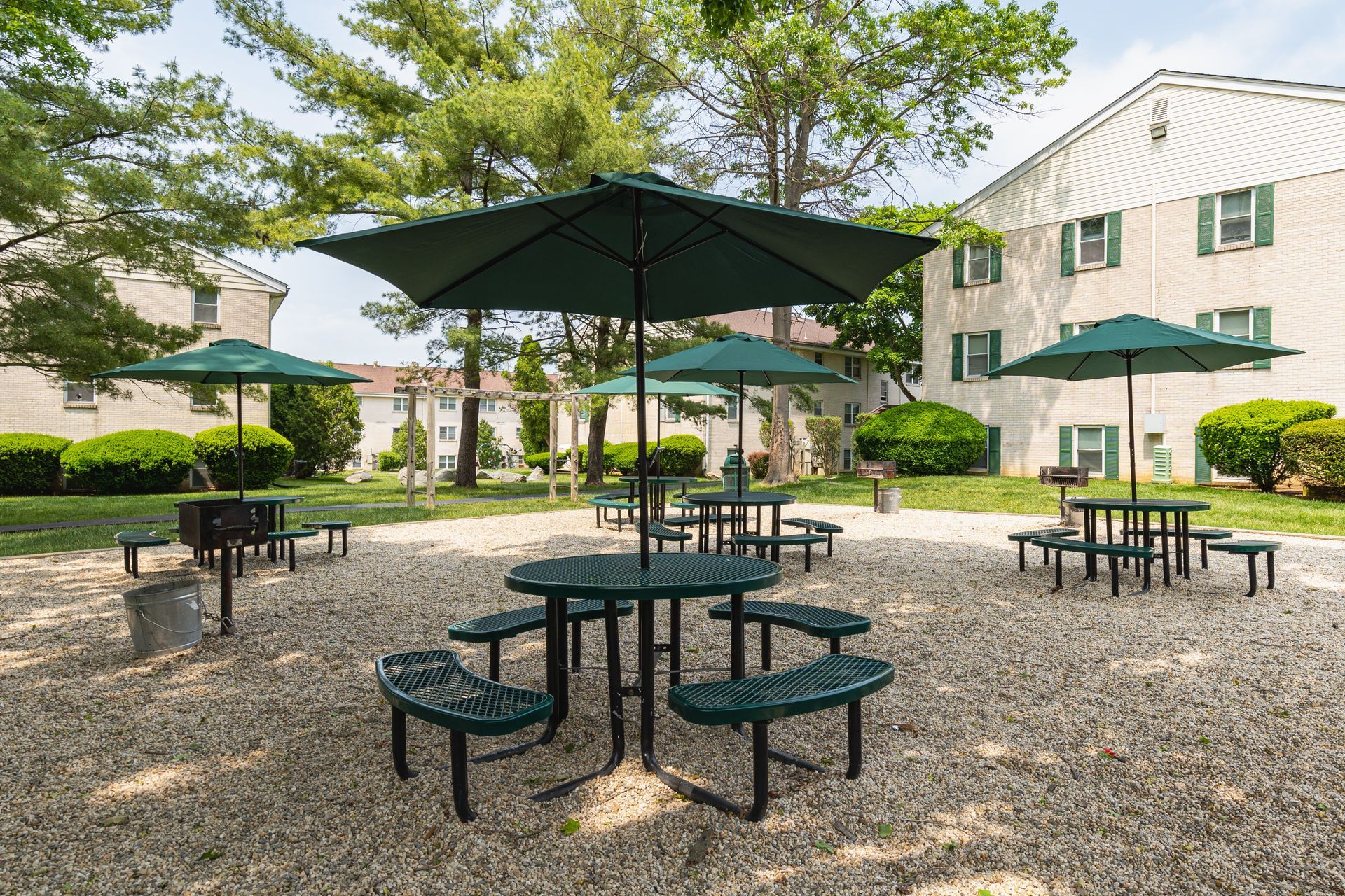 Brookbend Apartments Modern lounge area with fireplace, seating, and tables. Gray walls, green chairs, and black leather furniture.