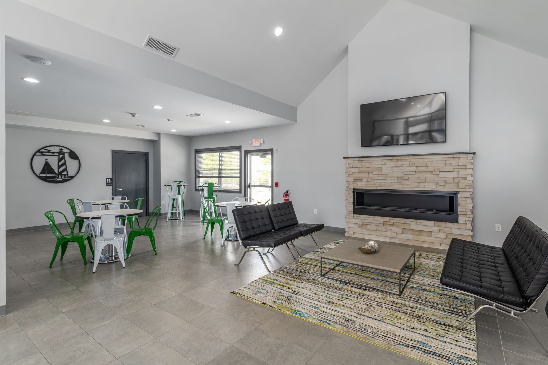 Brookbend Apartments Modern living room with fireplace, seating, tables, and logo on the wall.