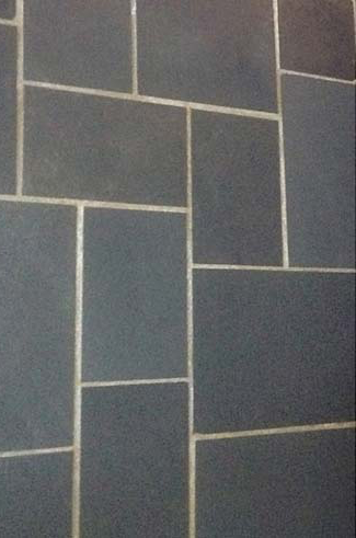 Accessible beige tiled shower with bench, grab bar, multiple shower heads and fixtures.