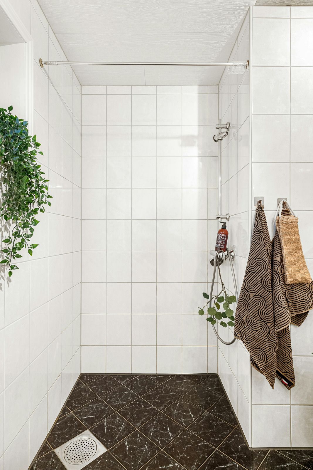 Accessible shower with grab bars, built-in seat, and multiple showerheads. Tan tiles, silver fixtures.