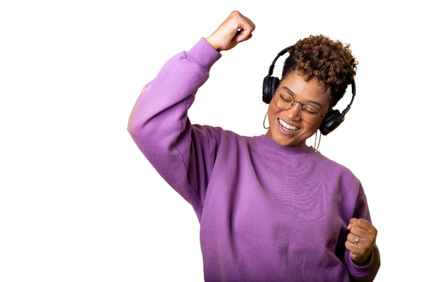 Woman in purple sweatshirt and headphones, eyes closed, fist raised in excitement.