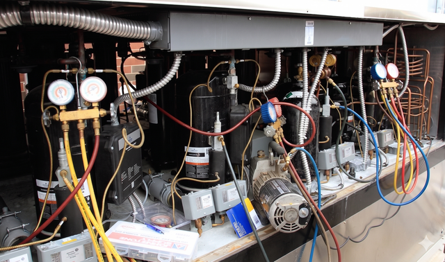 Open mechanical equipment with gauges, hoses, and wiring inside a metal cabinet