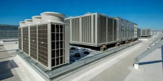 Modern rooftop view of a large white industrial building with vertical panels and blue sky