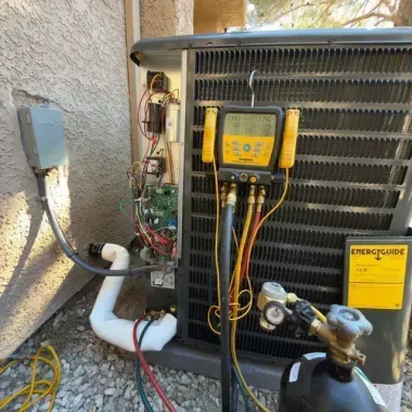 HVAC unit with yellow gauges and open side panel, showing wiring and refrigerant lines outdoors